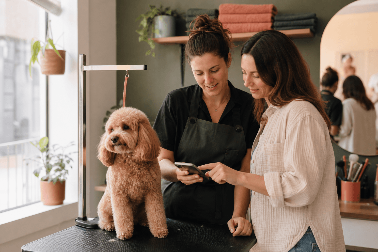A professional groomer and pet parent reviewing a visual reference together beside a calm dog